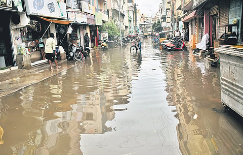 Residents wade through knee-deep floodwaters on Ponnuswamy Street in Royapettah, Chennai, on Wednesday