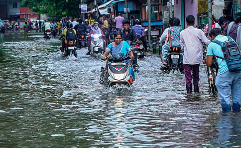 Commuters wade through a waterlogged street following heavy rain, in Chennai, Sunday, Oct. 18, 2026.