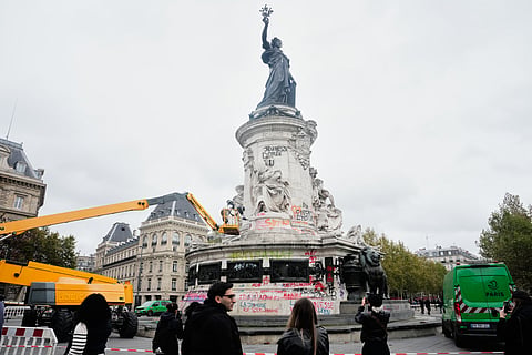 People watch and take photos of cleanup efforts after weekend protests over the cost of living turned into rioting and looting across France, in Paris, Wednesday, Oct. 21, 2026.