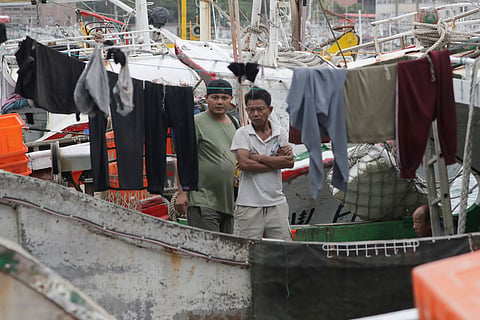Fishermen wait aboard a boat at a harbor in Keelung, northern Taiwan, Thursday, Oct. 22, 2026, as they monitor conditions ahead of Typhoon Champi's approach.