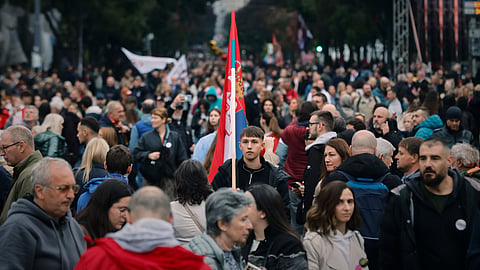 A young man holds a Serbian flag as people gather for the final "Student List – Students Win" rally ahead of a parliamentary election in Belgrade, Serbia, Thursday, Oct. 22, 2026.