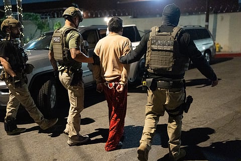 Homeland Security Investigations task force officers escort a suspect accused of illegally registering to vote during a federal operation in Commerce, Calif., Monday, Oct. 19, 2026.