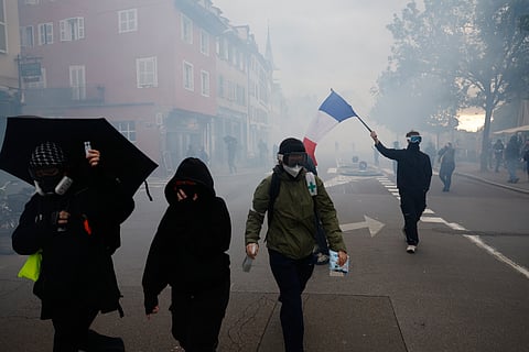 A protester holds a French flag during a demonstration against rising living costs in Strasbourg, France, Saturday, Oct. 24, 2026.