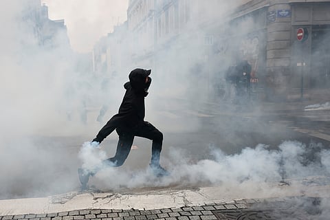 A protester throws a teargas canister to police after a demonstration against rising living costs in Rennes, France, Saturday, Oct. 24, 2026