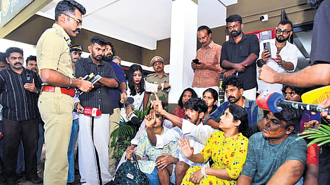 Bhadra Keerthi and Bharath Shankar, children of Jayabalakrishnan, along with relatives, speak to Kochi City DCP Arun K Pavithran during their sit-in protest in front of the Cheranalloor police station on Monday