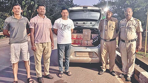 जप्त गोवा दारूसोबत बांदा पोलीस कर्मचारी. (छाया : विराज परब)