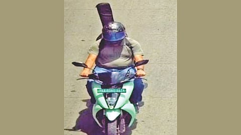 दुचाकीस्वाराच्या मागे दिसणारी गिटार.