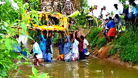 வாய்க்காலில் இறங்கி சடலத்தை தூக்கிச் செல்லும் அவலம்