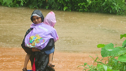 കോഴിക്കോട് വെള്ളംപൊങ്ങിയ പ്രദേശത്ത് നിന്നും കുഞ്ഞിനെയും വാരിയെടുത്ത് രക്ഷപ്പെടുന്ന യുവതി/ചിത്രം: എക്സ്പ്രസ്
