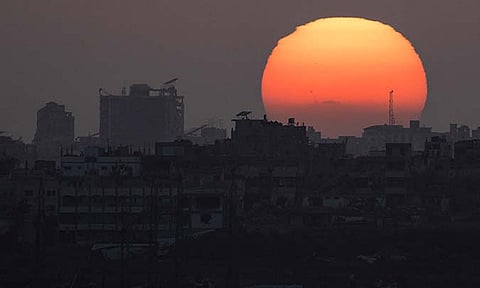 The sun sets behind the buildings in the Gaza Strip as seen from southern Israel, Saturday, June 29, 2024.