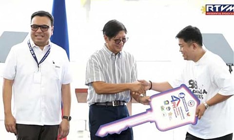 HOUSING FOR ALL. President Ferdinand R. Marcos Jr. hands over a symbolic key to a beneficiary during the Expanded Pambansang Pabahay para sa Pilipino (4PH) program milestone event and the 7th anniversary celebration of the Department of Human Settlements and Urban Development at the Megawide Pre-Cast Plant in Taytay, Rizal on Monday (Feb. 16, 2026). The ceremony highlighted the administration’s push to accelerate housing delivery through modern construction technology and expanded financing support. (RTVM screengrab)