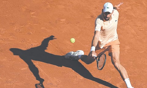 LOW FOREHAND. Novak Djokovic stretches for a low, wide forehand return during his grueling three-hour and 44-minute second-round victory over Valentin Royer at the French Open. Djokovic used ice packs around his neck and head during changeovers to keep cool and complete the win. /