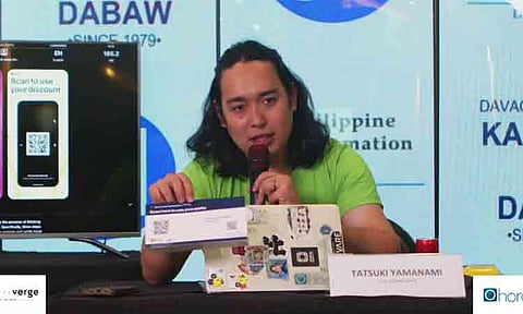 Tatsuki Yanamani, a Japan-based developer with Ohana ICT, demonstrates the new "Digital Davao Tourist Passport" mobile application during its official launching ceremony at SM City Davao Annex. The smart-mobility initiative, developed under the Smart JAMP framework, replaces the traditional physical tourism booklet with a digital platform featuring QR-coded discounts, interactive local maps, and tourism data tracking for visitors.