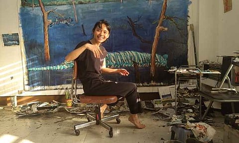 Filipino contemporary artist Breana Patricia "Bree" Jonson smiles as she sits in front of one of her signature large-scale nature paintings inside her art studio. Jonson passed away in September 2021 at the age of 30.