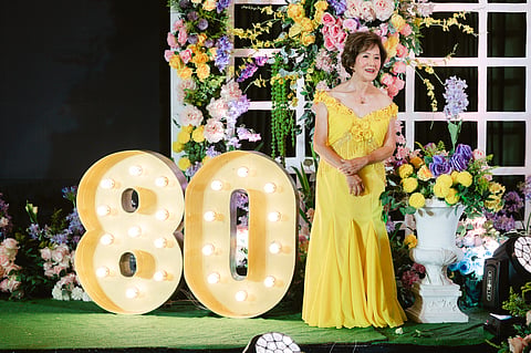 BIRTHDAY GIRL Maribel onstage among flowers and the figure 80.