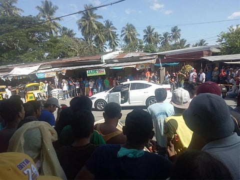 DAVAO. Gitapuk-an sa mga tawo ang kotse sa publisher sa weekly nga mantalaan human kini gipusil duol sa palengke sa Panabo City Huwebes, Hunyo 7. (Hulagway kuha ni Aileen Murcia)