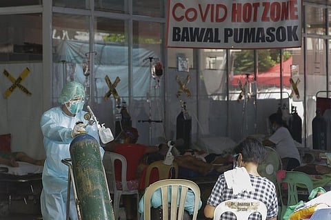 MANILA. A health worker wearing a protective suit pushes an oxygen tank outside the Amang Rodriguez Memorial Medical Center emergency area as they wait for rooms to be vacated in Marikina on March 26, 2021. (File)