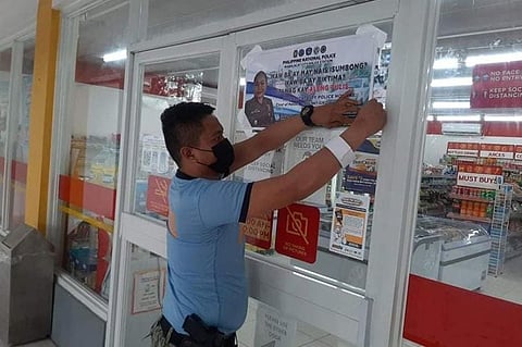 PAMPANGA. A policeman installs a poster with police hotlines as residents are encouraged to report crimes to the local police. (Mabalacat police photo)