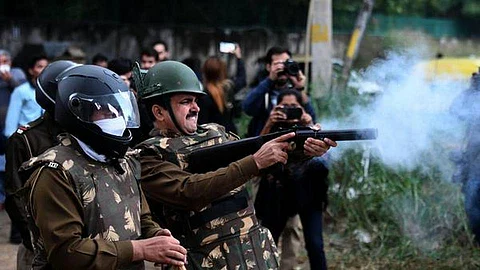 Policemen fire teargas during a stir by JMI students against the CAA in New Delhi.