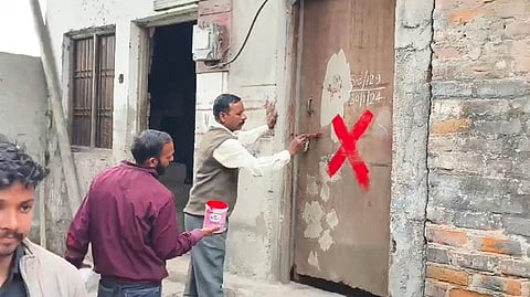 मकानों को तोड़ने के लिए रेड क्रॉस लगाते निगमकर्मी।