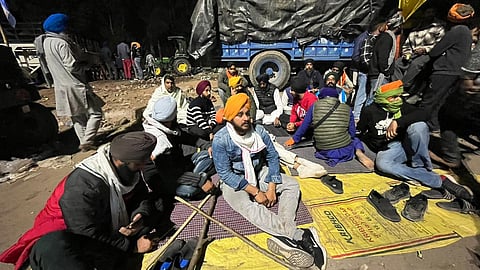सड़क पर तिरपाल बिछाकर बैठे किसान