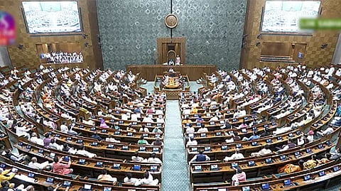 Aerial view of the Lok Sabha in session from behind the hall. MPs are seated in semi-circular rows raised like an amphitheatre. At the centre in front is the speaker.