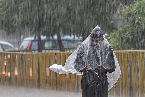 A person walking in rain with raincoat over their head