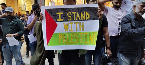 A protestor holding a placard with Palestine's flag and "I stand with Palestine" written