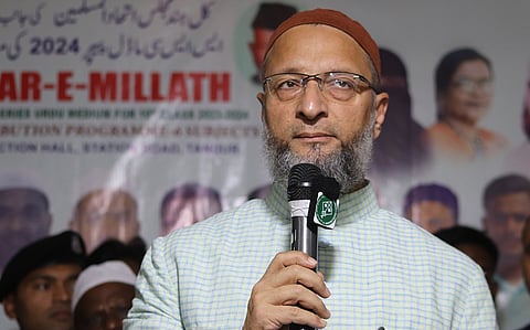 AIMIM president Asaduddin Owasi in a white and green chequered shirt speaking into a mic