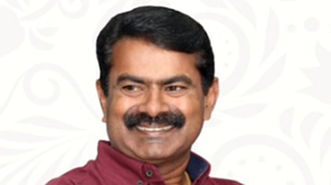 Naam Tamilar Katchi (NTK) president Seeman in a maroon shirt, in front of a white a bacground.