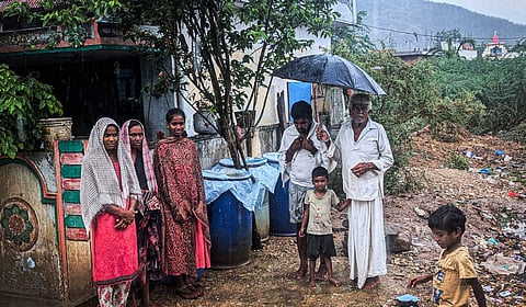 A family in Palnadu district's Bollapalli mandal stands next to cans which have been placed to collect rainwater.