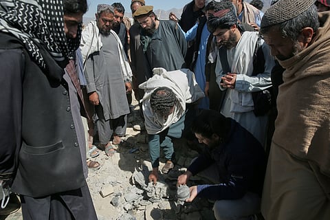 Residents and Taliban police gather the remains of a projectile at the site of a strike in Kabul, Afghanistan, Friday, March 13, 2026.