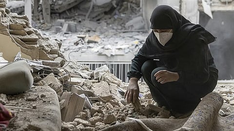 A woman sifts through the rubble in her home after it was damaged by a missile on March 15, 2026, in Tehran.