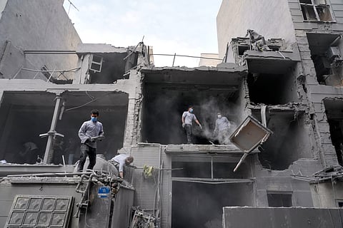 Volunteers clean debris from a residential building damaged when a nearby police station was hit Friday in a U.S.-Israeli strike in Tehran, Iran, Sunday, March 15, 2026.