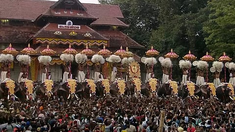 Kudamattam ceremony at Thrissur Pooram, with decorated elephants lined up in front of Thiruvambady Sri Krishna Temple as performers exchange colorful parasols before a large crowd