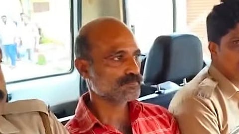 Sanish in a red checked shirt seated inside a police vehicle between two police personnel after being taken into custody in connection with a train abuse case.