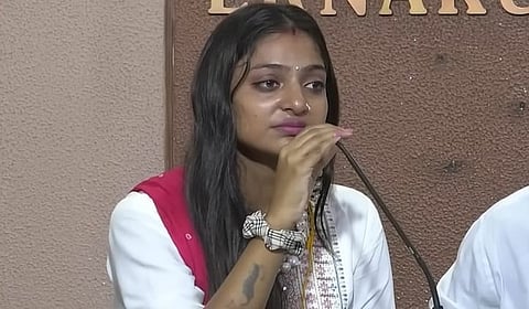 Monalisa Bhosle speaks into a microphone during a press conference in Kerala. She appears emotional while addressing reporters during the interaction.