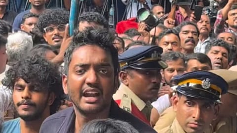 Chandu Salim Kumar is seen amid a crowd during the funeral of his father, Malayalam actor Salim Kumar. Police personnel and several people can be seen around him.
