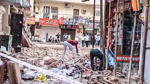 The site of the PG collapse. Some debris being removed by a single man. Most of the debris is cleared. Police tape visible