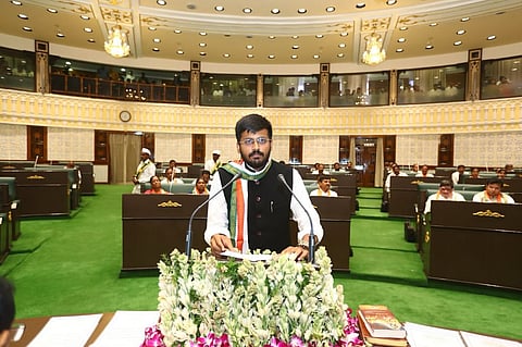 Indian politician Mynampally Rohith standing at a podium decorated with white flowers inside the Telangana Legislative Assembly hall.