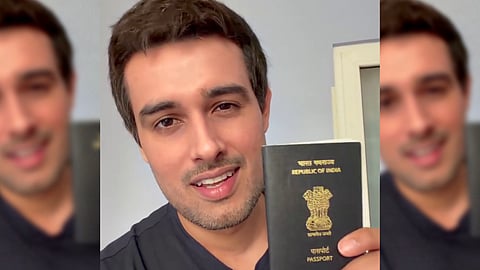 Indian YouTuber Dhruv Rathee wearing a black t-shirt, smiling while holding up a navy blue Indian passport showing the State Emblem of India and the words "REPUBLIC OF INDIA" and "PASSPORT" in gold lettering.