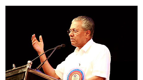 Pinarayi Vijayan speaking in front of a mike, his hand raised.