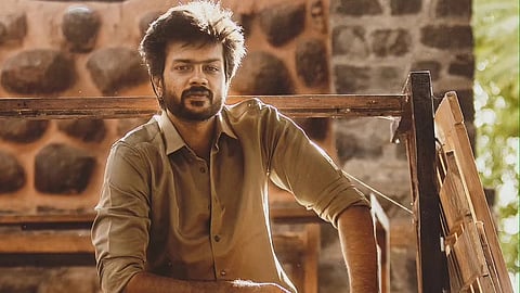 Image of Rishikanth wearing a brown shirt and black pants, seated on a chair