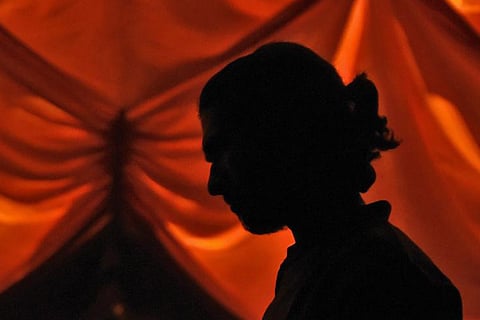 Shadow of side profile of a person standing against a read background