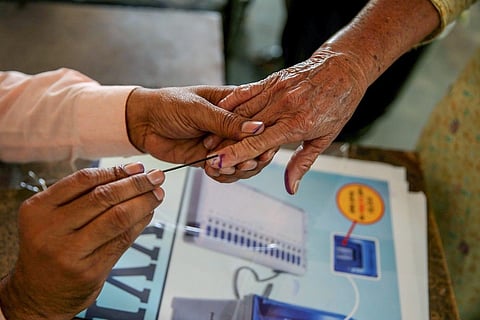 A person applying ink on another person's index finger