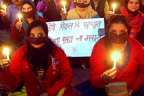 Two women at a candle light protest seen holding two candles