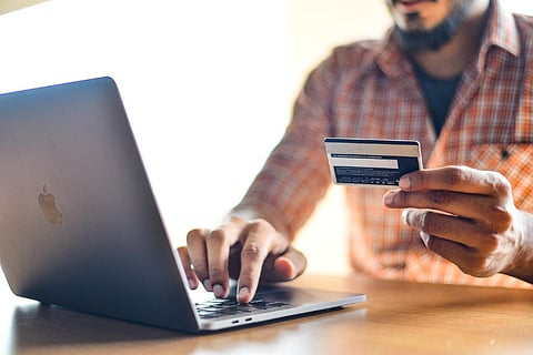 Representative image of a person using a credit card while typing into a laptop