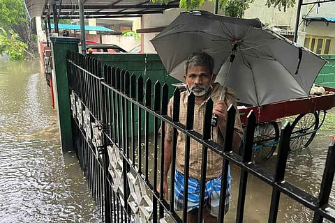 A man stands in knee deep water in Ashok Nagar in Chennai as heavy rainfall inundates streets and homes in the area