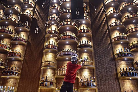 A bartender arranging liquor bottles: Kerala tweaks liquor policy, IT parks now allowed to serve alcohol