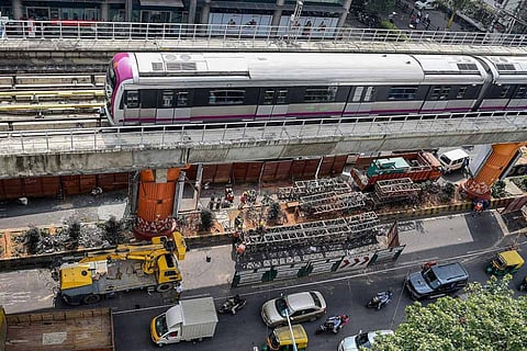 A Bengaluru metro train travels over city traffic below